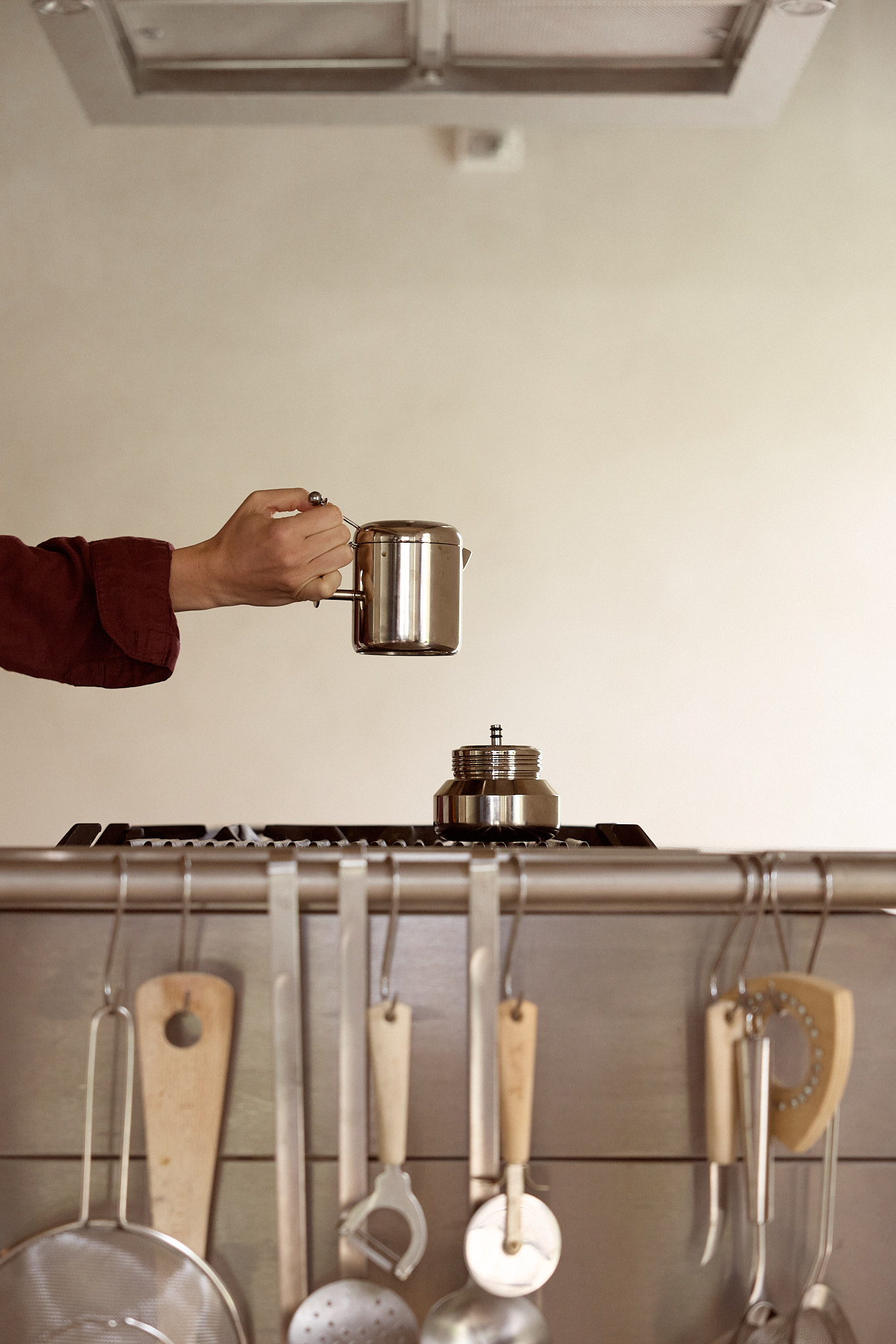 Detachable coffee pot being lifted from the Margot moka base in a kitchen